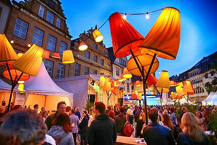 Besucher unter beleuchteten Ständen auf dem Leinewebermarkt in Bielefeld