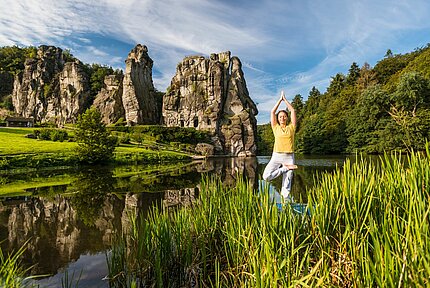 Frau macht Yoga vor den Externsteinen in Horn-Bad Meinberg